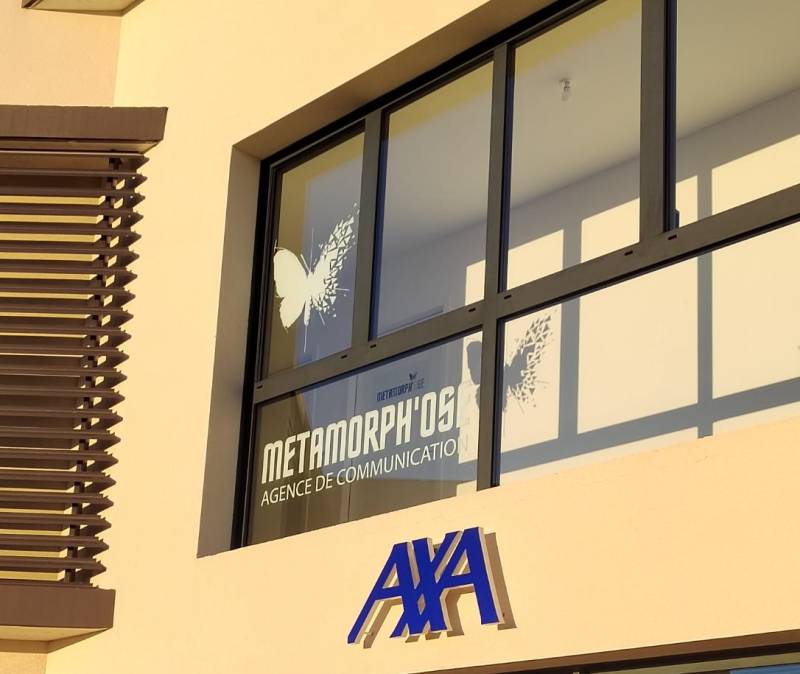 Vitrophanie de lettrage en film adhésif blanc en collage inversé, accompagné d'un papillon en film adhésif par impression numérique